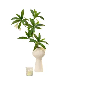Artistic white ceramic vase with horizontal texture and lush green artificial plant leaves