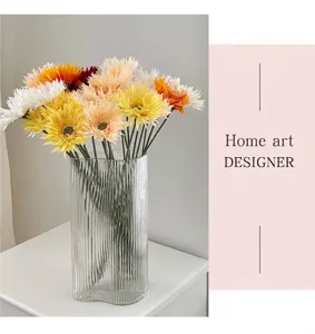 Detail von bunten Gerbera-Gänseblümchen in einer vertikal gestreiften Glasvase