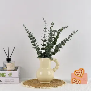 Feuilles d'eucalyptus artificielles dans un vase en céramique crème style minimaliste