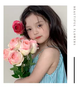 Close-up of pink artificial burnt roses with curled edges held by a girl in striped dress