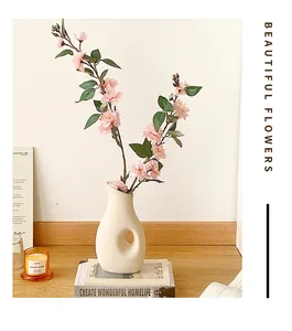 Rosa Kamelien-Kunstblumen in einer hohlen Keramikvase auf einem Holztisch