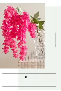Detailed view of hanging magenta wisteria silk flowers with green leaves in a clear vase