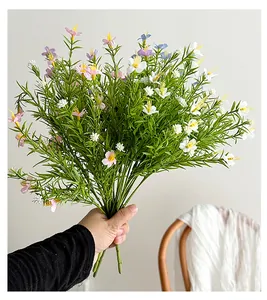 Close-up of hand-held colorful artificial baby breath flowers with realistic green leaves