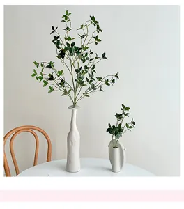 Vases minimalistes en céramique blanche avec texture verticale et tiges de feuillage vert