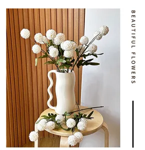 Detalle de crisantemo pompon blanco artificial en un jarrón de ondas sobre taburete