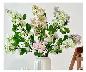 Detailed view of artificial lilac flowers in a white ceramic vase for home decoration