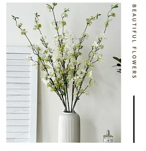 Detail of artificial white snow willow branches in a vertical striped ceramic vase