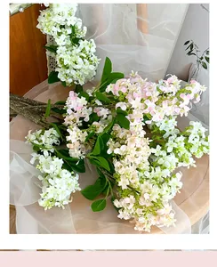 Detailed close-up of white and pink faux lilac blossoms with realistic green leaves
