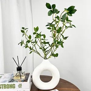 Vase anneau moderne en céramique blanche avec feuillage artificiel sur table bois