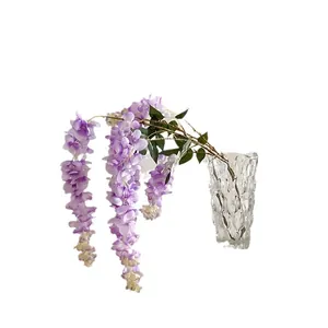 Artificial hanging wisteria vine with realistic purple flowers and green leaves in a vase
