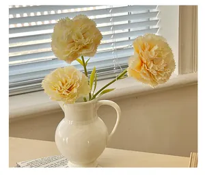 Detailed view of yellow artificial carnations in a white ribbed ceramic vase for home decor