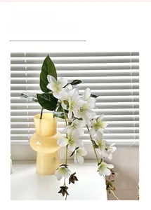 Lifelike white jasmine bouquet in a yellow glass vase on a bright sunny windowsill