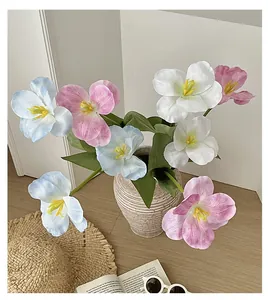 Detailed top view of pink and blue silk tulips in a textured ceramic vase on a wooden table
