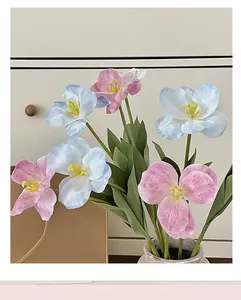 Close-up of light blue and purple artificial tulip silk flowers with realistic green leaves