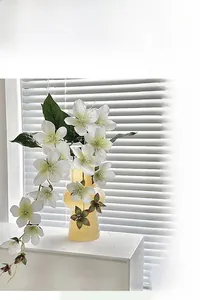 Artificial white jasmine flowers in a modern art glass vase on a window sill