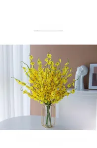 Vibrant yellow dancing lady orchid silk flowers in a gold metal frame vase on a desk