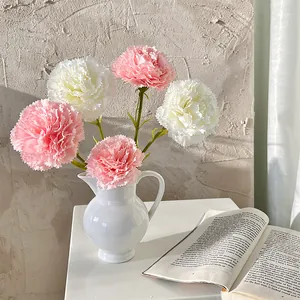 Artificial pink and white carnation bouquet in a white ceramic vase for home decoration