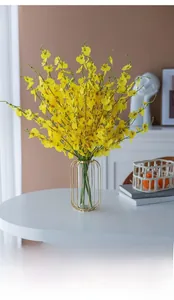 Macro detail of yellow artificial orchids in a modern gold and glass decorative vase