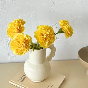 Artificial yellow carnations in white ceramic vase for home and bedroom decoration