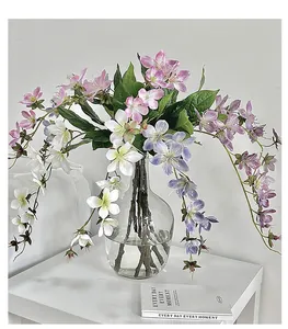 Detail of 3D printed silk Jasmine flowers in a glass vase with hanging green leaves