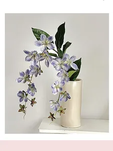 Detailed view of artificial purple jasmine flowers hanging in a white ceramic vase for decor
