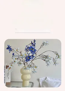 Dettaglio di margherite finte viola in vaso di ceramica beige per arredo tavola