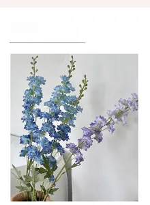 Close-up of blue and purple artificial delphinium flowers in a ceramic vase decor