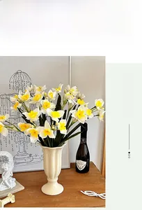 Bouquet de narcisses artificiels dans un vase en céramique sur une table en bois
