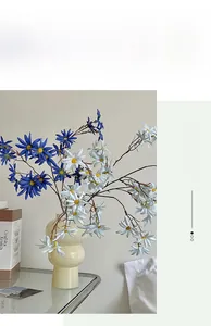 Dettaglio di margherite di seta bianche e blu a stelo lungo in un vaso moderno