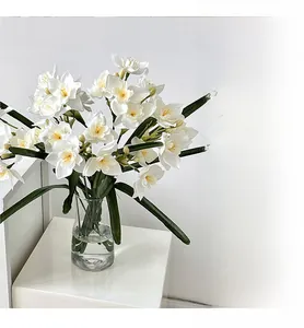 Détail de narcisses artificiels blancs dans un vase en verre pour une déco minimaliste