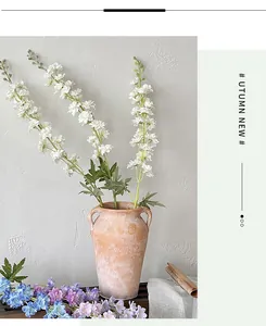Detail of white artificial delphinium flowers in a vintage ceramic vase for home decor