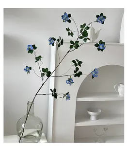 Detail of blue artificial apricot flowers with yellow pistils in a glass vase