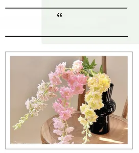 Pink and yellow silk larkspur flowers in black vase on a vintage wooden stool