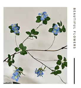 Close-up of artificial blue flowers with yellow stamens and green leaves for home decor