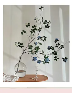 Detail of lifelike white and blue faux flowers in a glass vase with window shadows