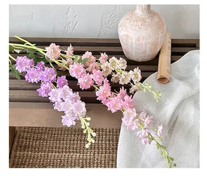 Detailed view of colorful faux delphinium flowers on a rustic wooden bench background