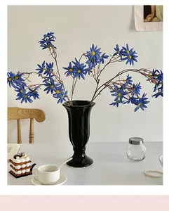 Fiori artificiali blu in un vaso di ceramica nera per la decorazione della tavola