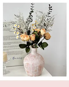 Detail van roze-witte keramische vaas met een boeket van rozen en witte madeliefjes