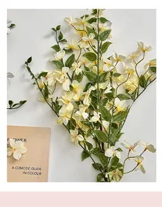 Detalle de flores amarillas artificiales con hojas verdes sobre un fondo blanco puro