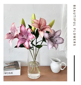 Close-up of artificial 3D lilies with realistic petals in a clear glass vase on wood