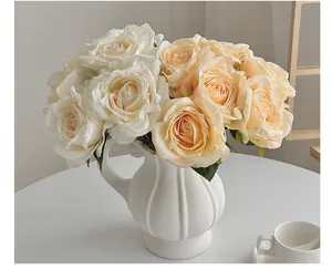 Détail de roses artificielles crème et champagne dans un vase en céramique blanche