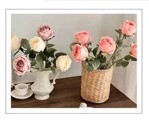 Detail of pink and champagne artificial roses in a white ceramic vase on wooden table
