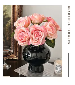 Gros plan de roses artificielles roses dans un vase en céramique noire brillante