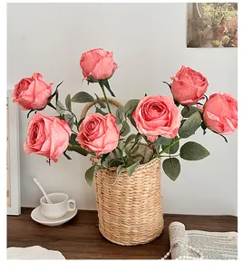 Pink artificial roses set in a straw basket on a dark wood table with vintage decor