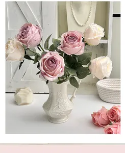 Close-up of pink and cream faux roses in a white ceramic vase with realistic petals