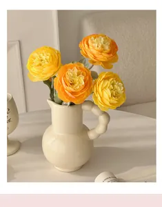 Detailed view of faux ranunculus flowers in a modern cream ceramic vase for home decor