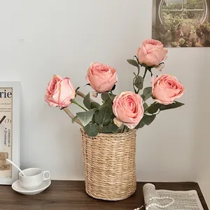 Pink artificial roses in a woven basket for home tabletop decoration and photography