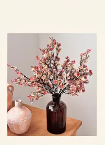 Detalle de flores de paniculata de seda rosa y naranja en un jarrón de cristal marrón en una mesa
