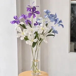 Kunstmatig clematis boeket in blauw en paars in glazen vaas op houten kruk