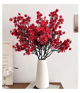 Detailed close-up of silk red gypsophila flowers in a modern white ceramic vase